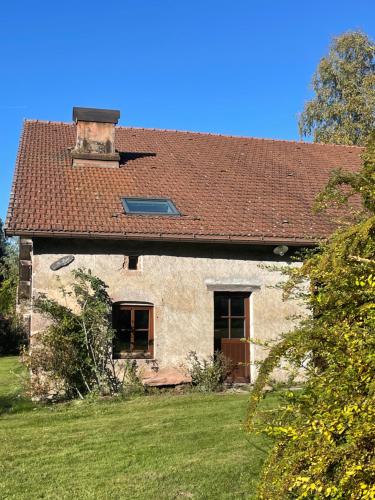una antigua casa de piedra con techo rojo en La Hutte, en Tendon