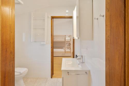 a white bathroom with a toilet and a sink at ABLA Guest House in Carcavelos