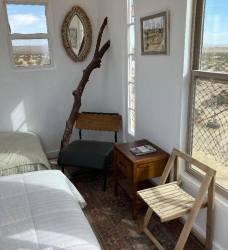 a bedroom with a bed and a chair and a window at Treehouse in Joshua Tree