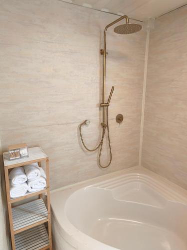 a bathroom with a tub and a shower with towels at הzimער של ביטון in Merhav Am
