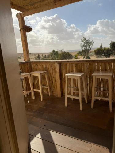 a porch with four white stools on a deck at הzimער של ביטון in Merhav Am