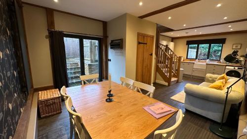 a dining room with a wooden table and a couch at Cuckoo Penn Hideaway - Luxury Cotswold Retreat in Gloucestershire