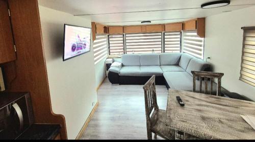 a living room with a couch and a table at Le Petit Écrin, caravane résidentielle in Trois-Ponts