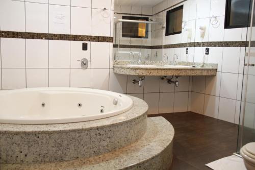 a bathroom with two sinks and a bath tub at Buriti Hotel in Jataí