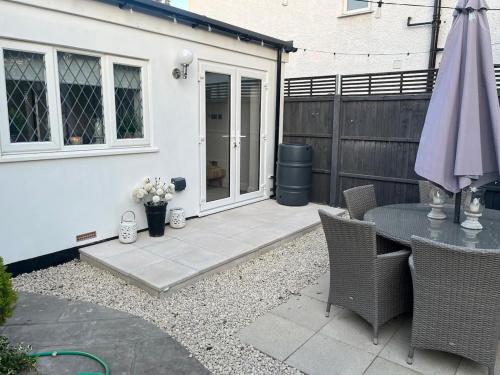 a patio with a table and an umbrella at Garden Lodge, boutique - Walton on Thames in Walton-on-Thames