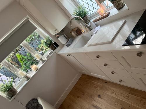 an attic kitchen with white cabinets and a window at Garden Lodge, boutique - Walton on Thames in Walton-on-Thames