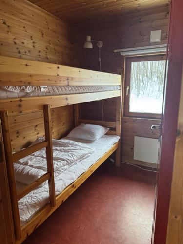 two bunk beds in a wooden room with a window at Skutstuga 2 - Gruvbacken Huså in Järpen