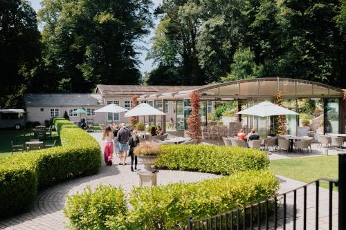 a group of people walking through a garden with umbrellas at The Coed-Y-Mwstwr Hotel in Bridgend