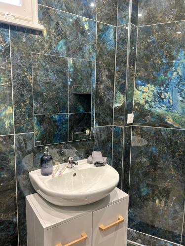 une salle de bains avec un lavabo et un mur en mosaïque dans l'établissement Bentley studio, à Sanary-sur-Mer