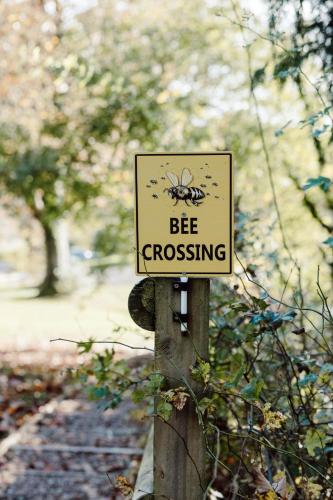 a bee crossing sign on a wooden pole at The Coed-Y-Mwstwr Hotel in Bridgend