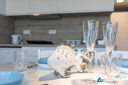 a silver fish statue sitting on a table with two wine glasses at 365PAM - Kolory Lata - KLIMATYZACJA, PLAC ZABAW, GRILL in Sarbinowo