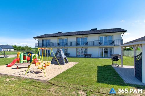a yard with a playground and a house at 365PAM - Kolory Lata - KLIMATYZACJA, PLAC ZABAW, GRILL in Sarbinowo