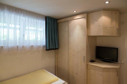 a room with a bed and a tv and a window at Alpenhaus Montafon by Pferd auf Wolke in Gargellen
