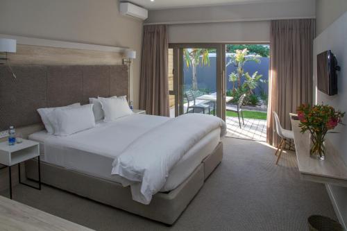 - une chambre avec un grand lit blanc et un balcon dans l'établissement Ocean Bay Guesthouse, à Port Elizabeth