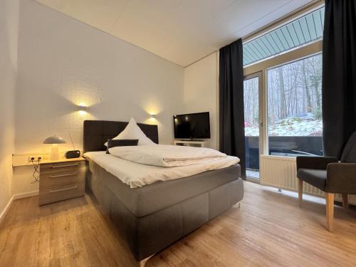 a bedroom with a bed and a large window at Kurhaus im Harz - Bad Harzburg in Bad Harzburg