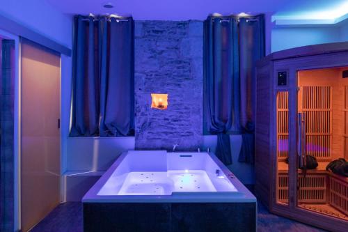 a large bath tub in a room with blue curtains at LX202 Love Room & Spa privatif - Jacuzzi & Sauna in Dijon