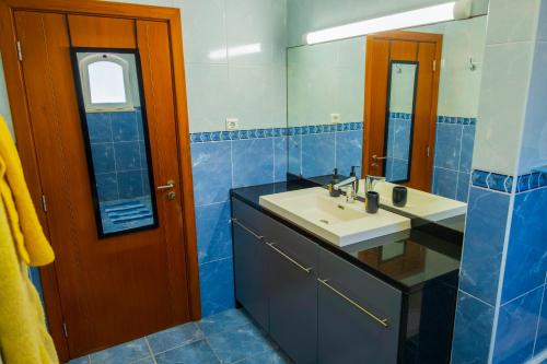 a blue tiled bathroom with a sink and a mirror at Verde Verdilhão Villa in Arazede