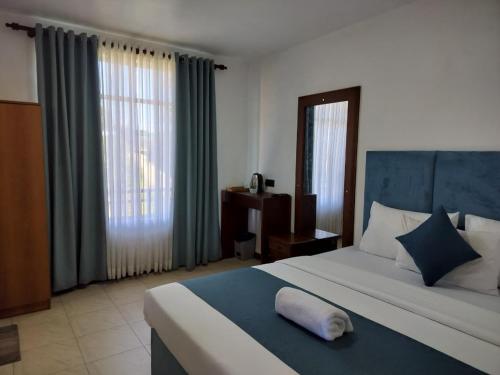 a bedroom with a large bed with a blue headboard at Ru Hotel & Villa in Nuwara Eliya