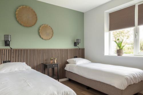two beds in a bedroom with a window at Luxe appartement 4 personen #2