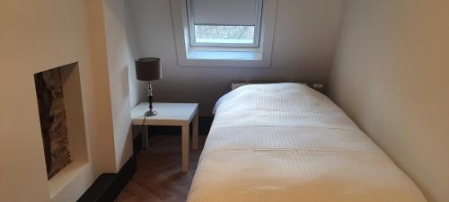 a small bedroom with a bed and a small table at B&B Velddriel in Velddriel