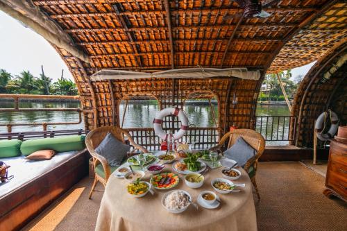 a table with plates of food on a boat at Spice Coast Cruises - Houseboat, A CGH Earth Experience in Alleppey