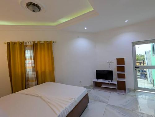 a bedroom with a bed and a tv and a window at Refuge Des Princes in Douala