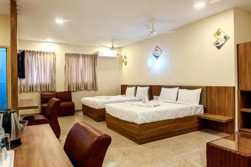 a hotel room with two beds and a couch at Hotel M S Chola in Chennai