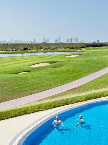two people in the water in a swimming pool at Golf view living by FlamingoAmber Dubai in Ajman