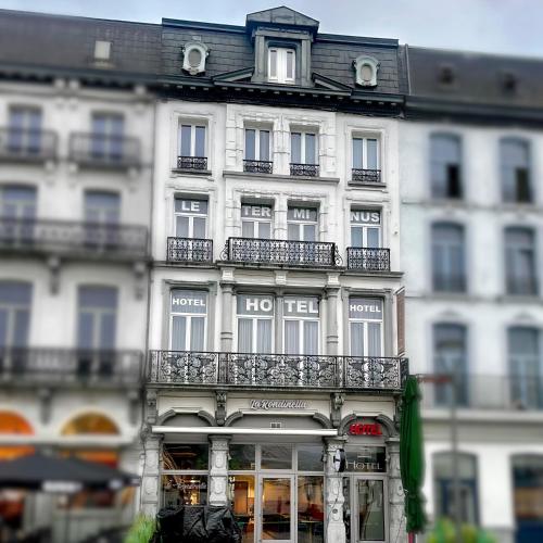 a tall white building with balconies on the side of it at Hotel Le Terminus in Mons