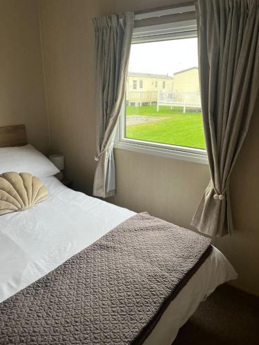 a bedroom with a bed and a window at Caravan at the seaside in Great Yarmouth