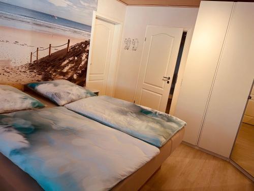 two beds in a room with a painting of a beach at Ferienwohnung Dietje in Stedesdorf