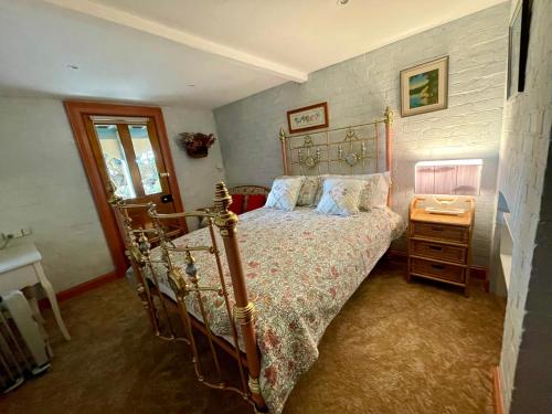 a bedroom with a bed and a dresser with a night stand at Elsmere Heritage Gardens & Accom in Launceston