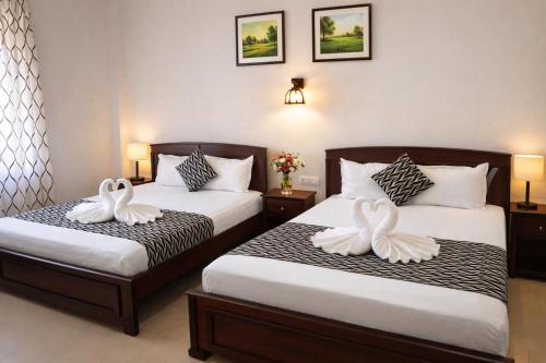 two beds in a hotel room with white towels at Blue Diamond Resort in Trincomalee