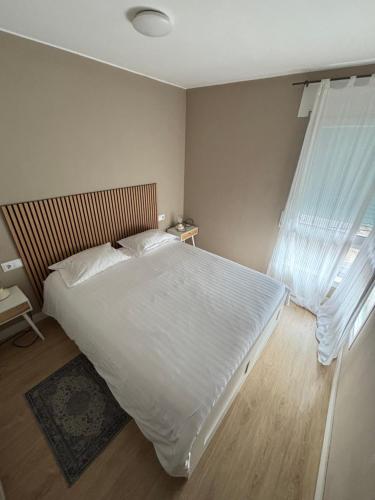 a bedroom with a large white bed and a window at Cardedeu City and Circuit apartment in Cardedeu