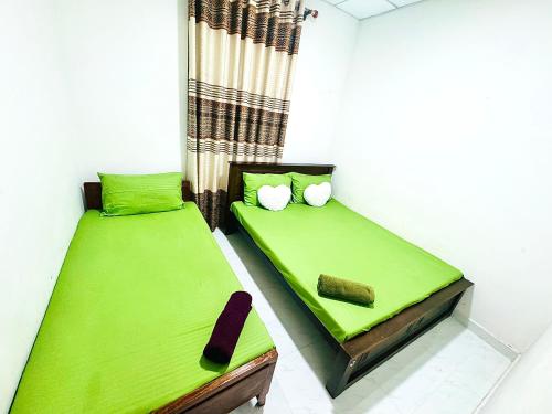 two beds in a room with green sheets at D2 Holiday Inn in Badulla