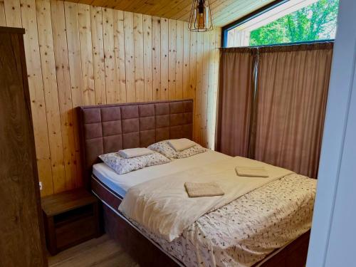 a bed in a wooden room with a window at Šumska Duša in Banja Luka