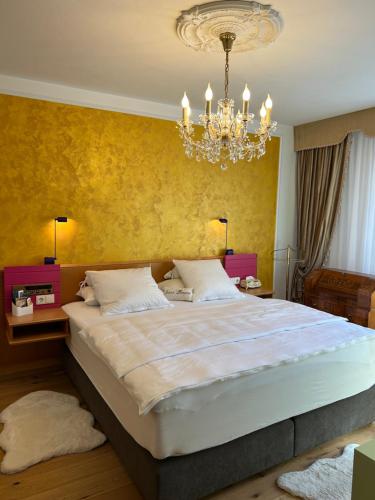 a bedroom with a large bed and a chandelier at Golden Rooms Exklusiv in Völkermarkt