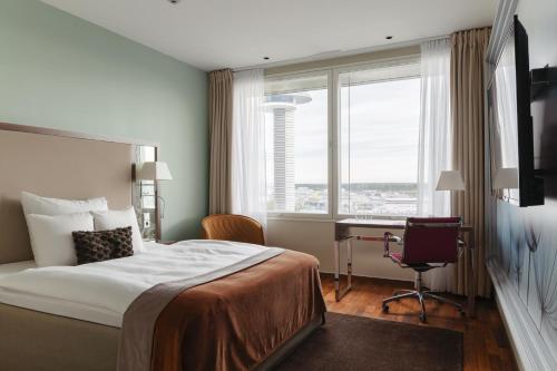 a hotel room with a bed and a desk and a window at Clarion Hotel Arlanda Airport Terminal in Arlanda