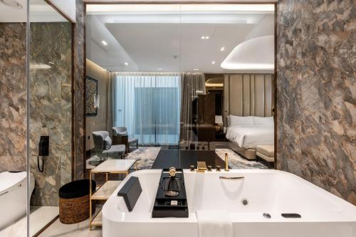 a bathroom with a bath tub and a bedroom at The Biltmore Hotel Villas Dubai in Dubai