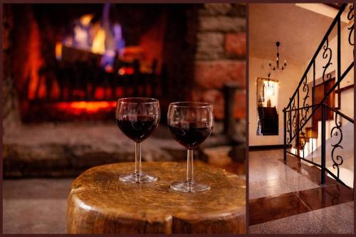 two glasses of red wine sitting on a table with a fireplace at BIESIADA in Korbielów