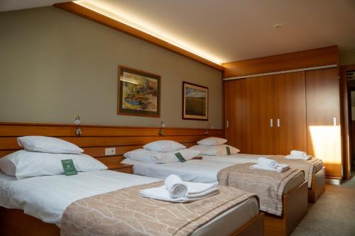 a hotel room with three beds with hats on them at Hotel Club Tisza in Lakitelek