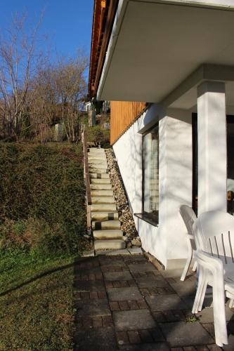 a patio with a white chair and stairs to a house at Ferienhaus Alpkönig in Missen-Wilhams