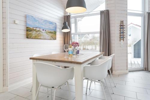 a dining room with a table and white chairs at Nordstern in Schönberger Strand