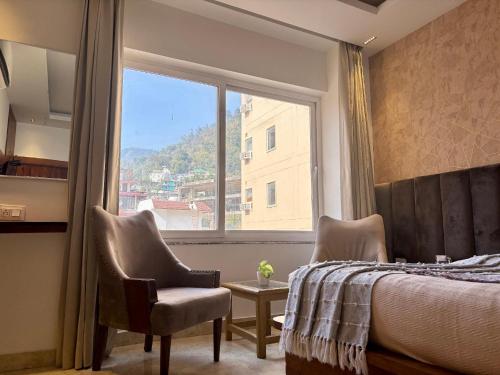 a bedroom with a bed and two chairs and a window at Vyom Boutique Hotel by Aramah in Rishīkesh