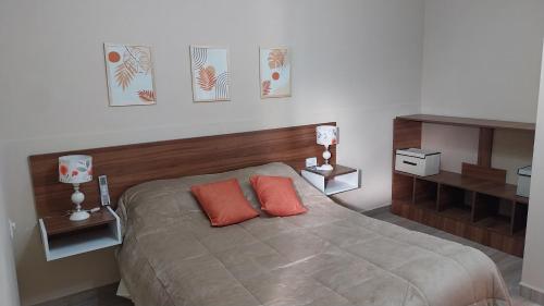 a bedroom with a bed with two orange pillows at Complejo Los Tilos in Chascomús