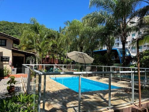 a swimming pool with an umbrella next to a resort at Chalés do Holandês Eco Pousada in Bombinhas