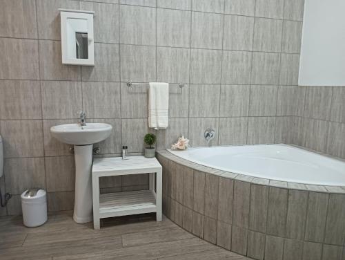 a bathroom with a bath tub and a sink at Oakwood Lodge in Bloemfontein