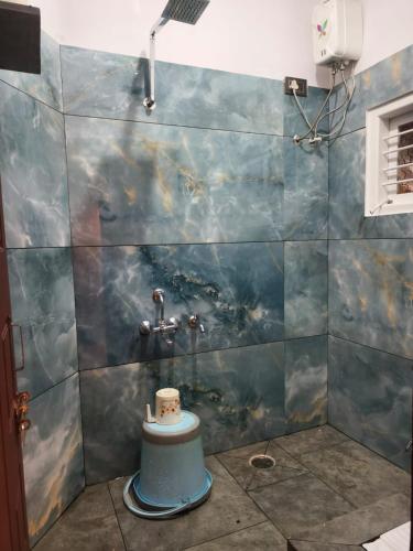 a bathroom with a shower with a blue tile wall at Tranquil service apartment in Chikmagalūr