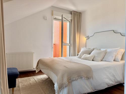 a white bedroom with a large bed and a window at Dúplex Mies de Usgo in Miengo