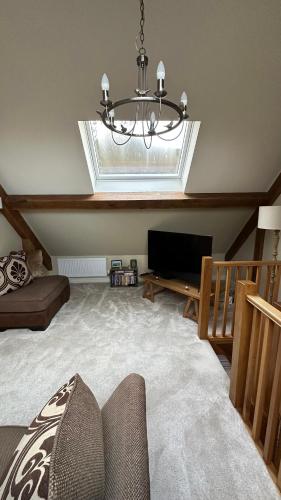 a living room with a chandelier and a television at Cuckoo Penn Hideaway - Luxury Cotswold Retreat in Gloucestershire
